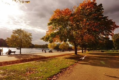 Footpath by road against cloudy sky