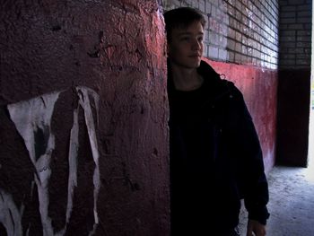 Portrait of young man standing against wall
