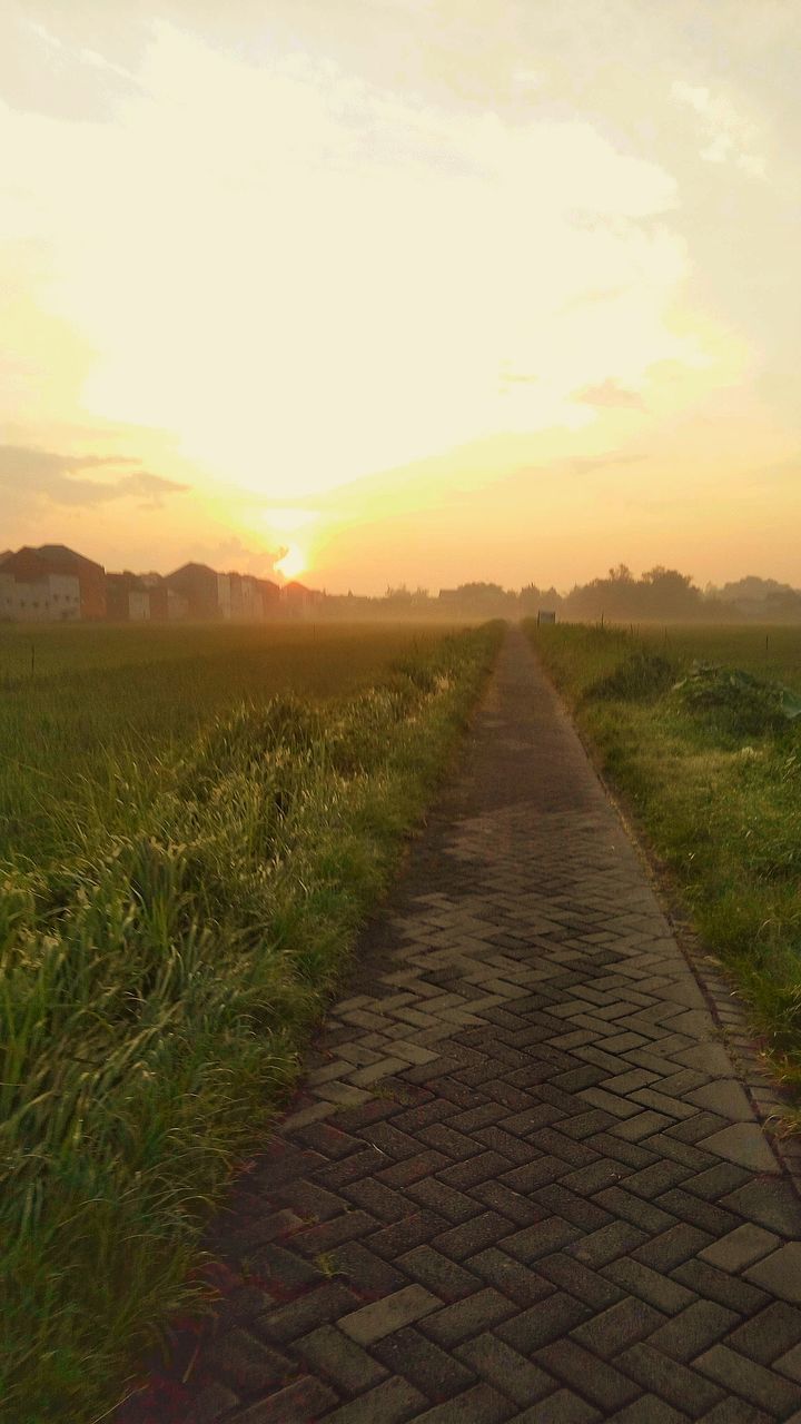 EMPTY FOOTPATH AMIDST FIELD AGAINST SKY AT SUNSET