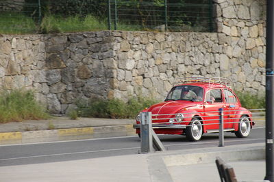 Red vintage car on road against wall