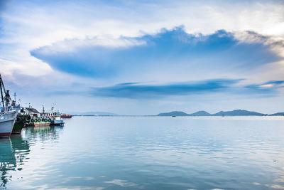 Sailboats in sea against cloudy sky