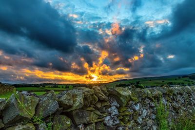 Scenic view of agricultural field against dramatic sky