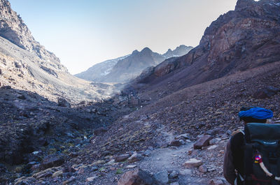 Rear view of man walking on rock against sky