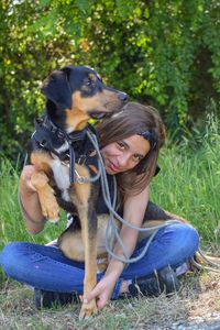 Young woman with dog sitting on land