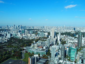 High angle view of modern buildings in city against blue sky