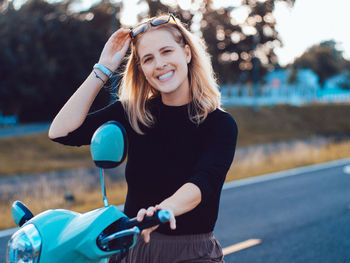 Portrait of young woman sitting on motor scooter