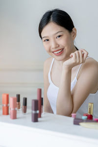 Portrait of smiling young woman with beauty product on table at home