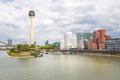 View of buildings at waterfront against cloudy sky