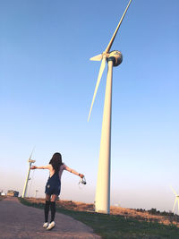 Full length of young woman standing on field against clear sky