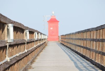 Footpath by lighthouse against clear sky