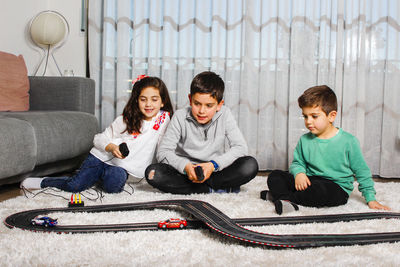 Siblings playing with toy while sitting at home