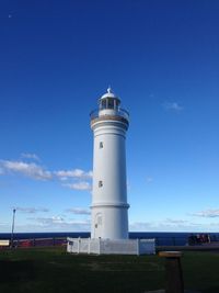 Low angle view of lighthouse by building against sky