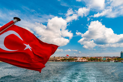 Red flag by buildings against sky in city