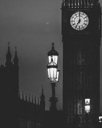 Low angle view of clock tower against building at night