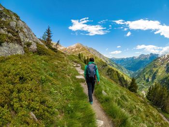 Woman hiking on footpath in the austrian alps near gastein, salzburg, austria