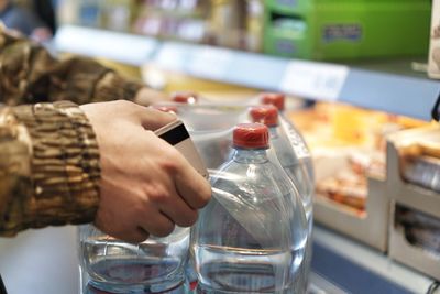 Midsection of woman holding glass bottle