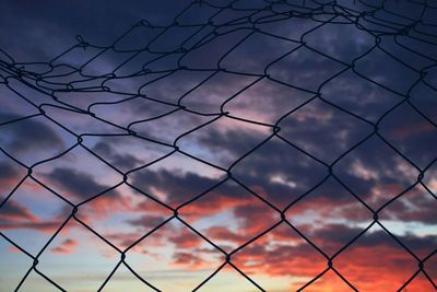 Full frame shot of chainlink fence against sky during sunset