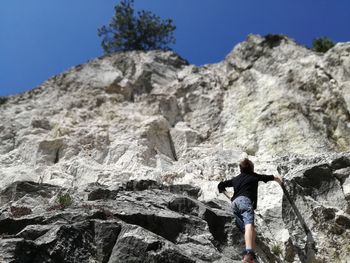 Low angle view of boy climbing mountain