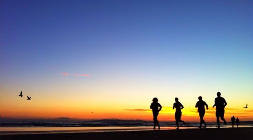 Silhouette of people on beach at sunset