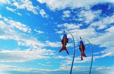 Low angle view of flags hanging against blue sky