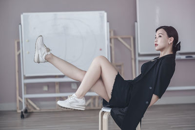 Side view of young woman sitting on table