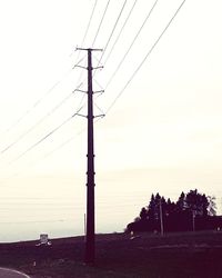 Silhouette electricity pylon on land against sky during sunset