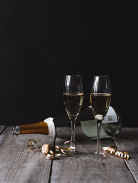 Two glasses of champagne and empty bottle with black background.