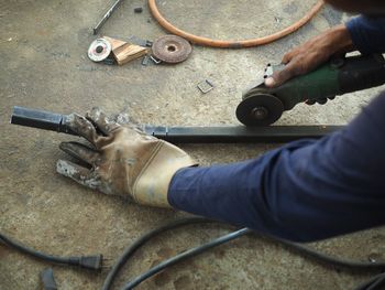 Cropped hands of male worker cutting metal at workshop