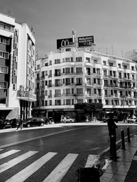 Man crossing road against buildings in city