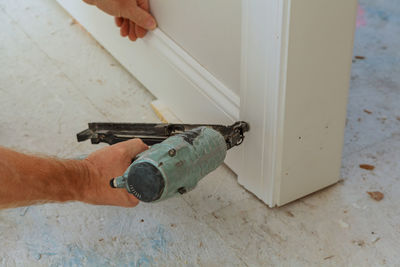 Close-up of cropped hand using nail gun on wood