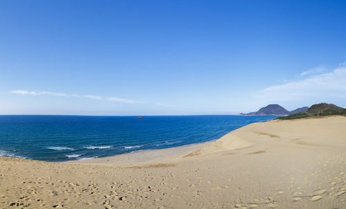 Scenic view of beach against blue sky