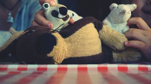 Cropped hands holding stuffed toys on bed