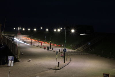 Empty road along illuminated street lights at night