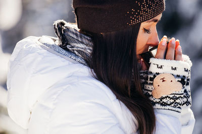 Young woman having drink while standing on snow covered mountain