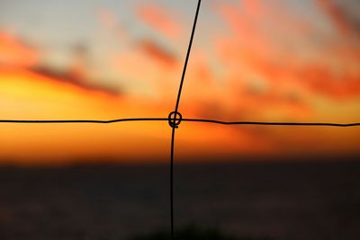 Close-up of barbed wire against sky at sunset