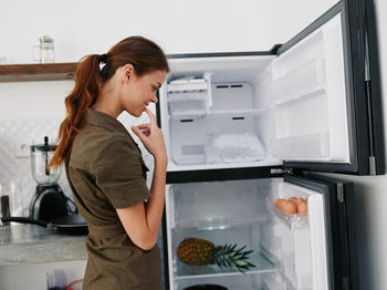 Side view of young woman standing in kitchen