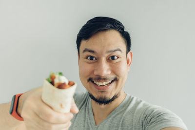 Portrait of smiling man with ice cream against white background