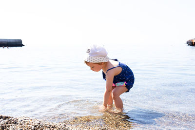 Rear view of boy playing in sea against clear sky