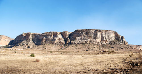 Rock formations on landscape against clear blue sky