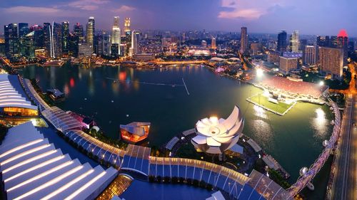 Illuminated cityscape against sky seen through marina bay sands during sunset