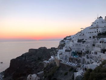 Buildings by sea against sky during sunset