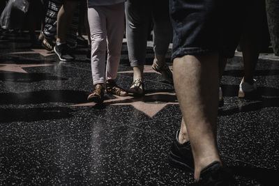 Low section of people walking on street in city