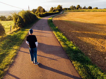 Aerial view of man on country road. rear view of man on road amidst fields