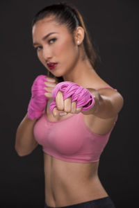 Young woman looking away while standing against black background