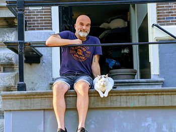 Man with cat sitting outside at the amsterdam canals