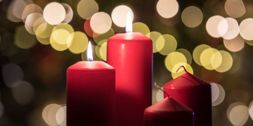 Close-up of illuminated candles against christmas lights