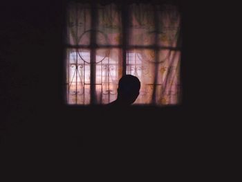 Silhouette of person standing in dark room