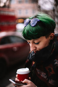 Portrait of hipster woman using smart phone while standing in city