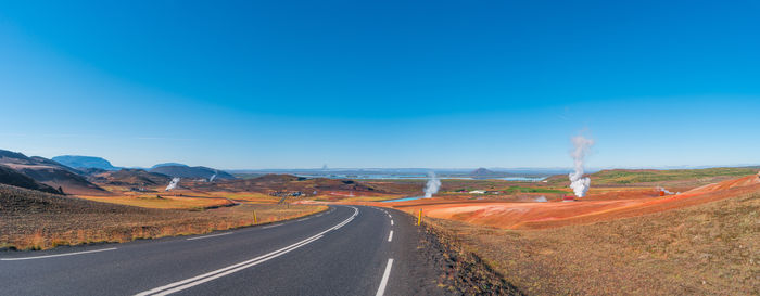 Road amidst landscape against clear blue sky