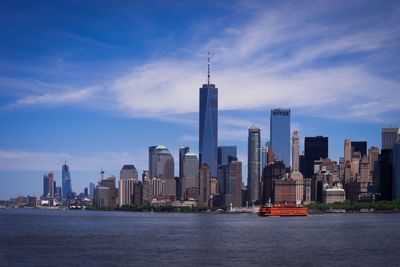 Sea by modern buildings against sky in city
